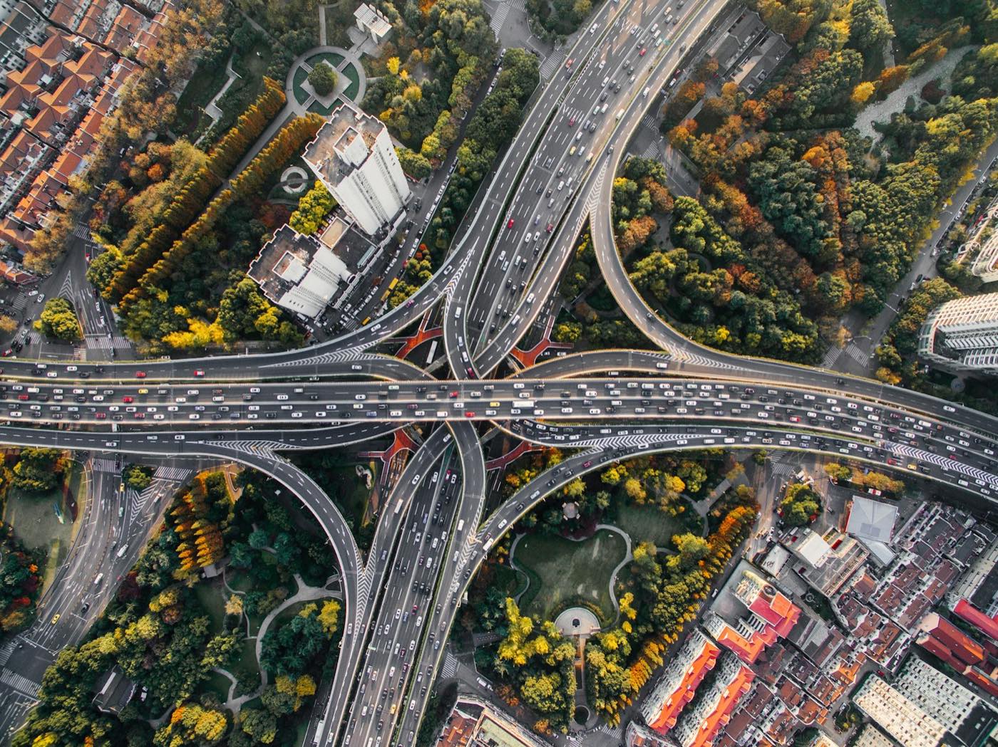 Vista aérea de um entroncamento urbano com centenas de veículos em movimento